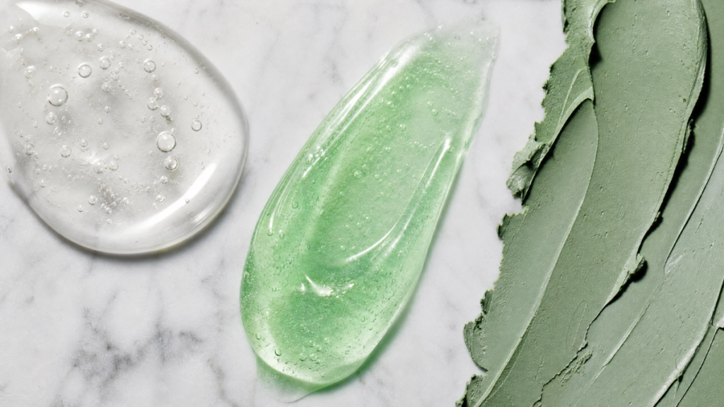Close-up de texturas de produtos de skincare para pele oleosa, incluindo gel de limpeza, sérum e máscara de argila sobre mármore.